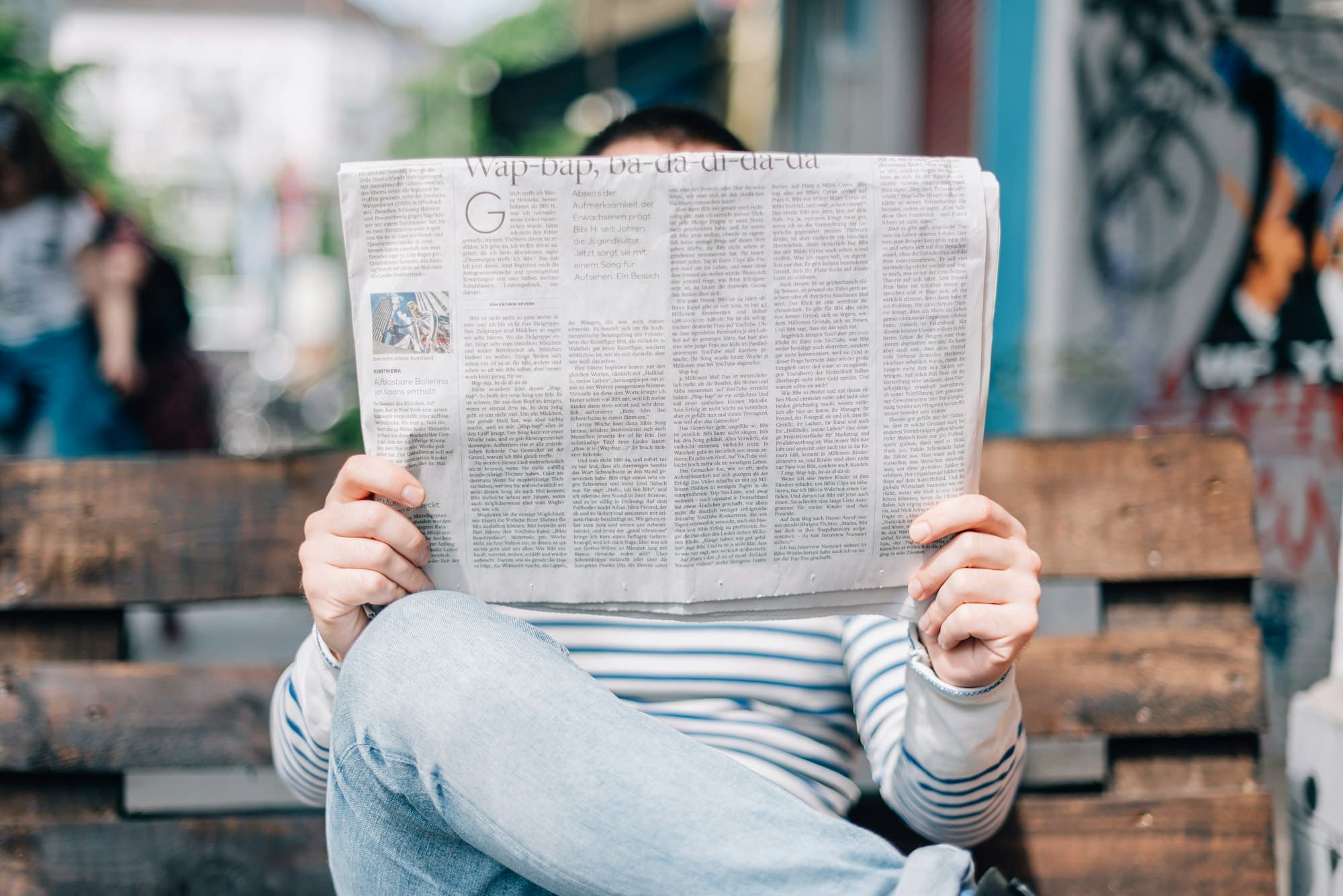 A person reading a newspaper in a public place